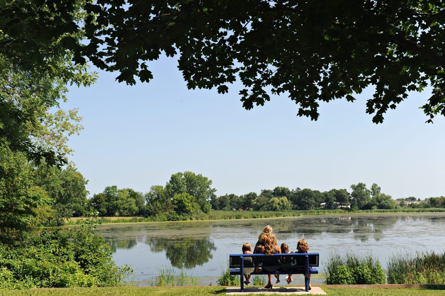 Family Sitting on Bench Infront of Pond